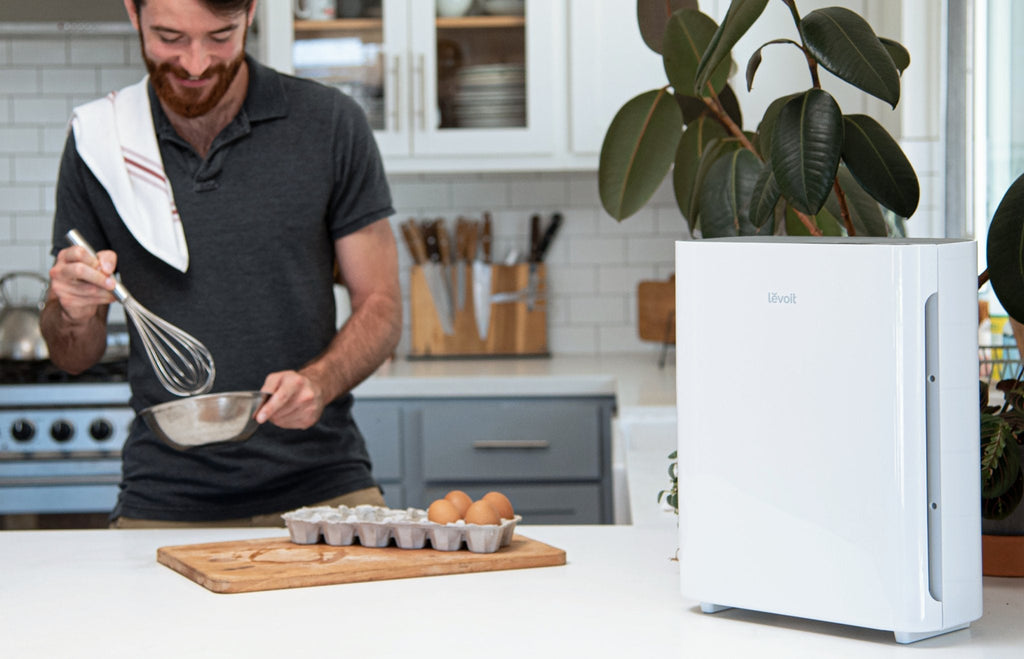 Levoit air purifier in a kitchen setting, with a person whisking ingredients, showing the appliance's effectiveness in maintaining clean air.